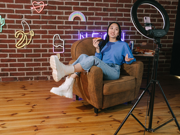 An influencer sitting on a couch in front of a ring light creating marketing material