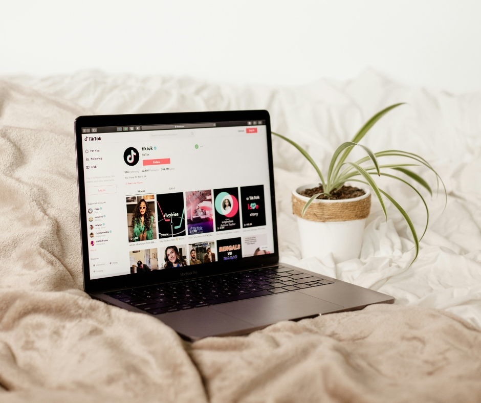 Photo of a laptop sitting on a bed, with a TikTok account showing on the screen.